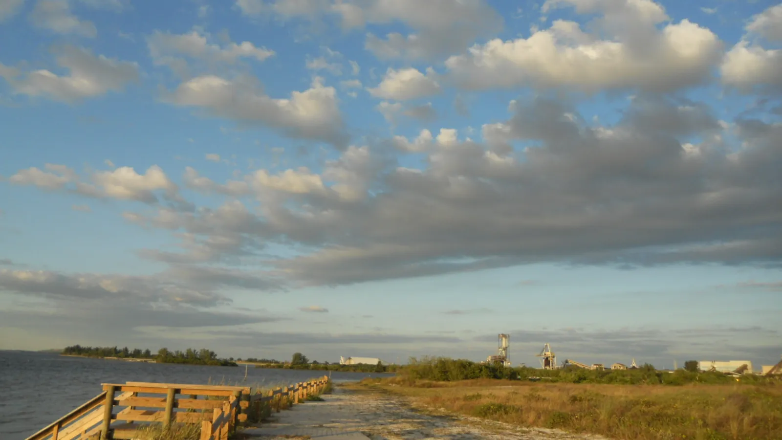 A shoreline path and wooden railing beside Tampa Bay in Apollo Beach, Florida