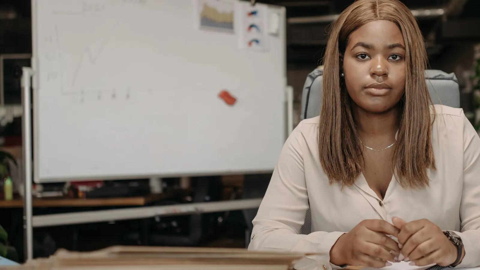 Office manager seated at a desk with stacks of paperwork in a small office