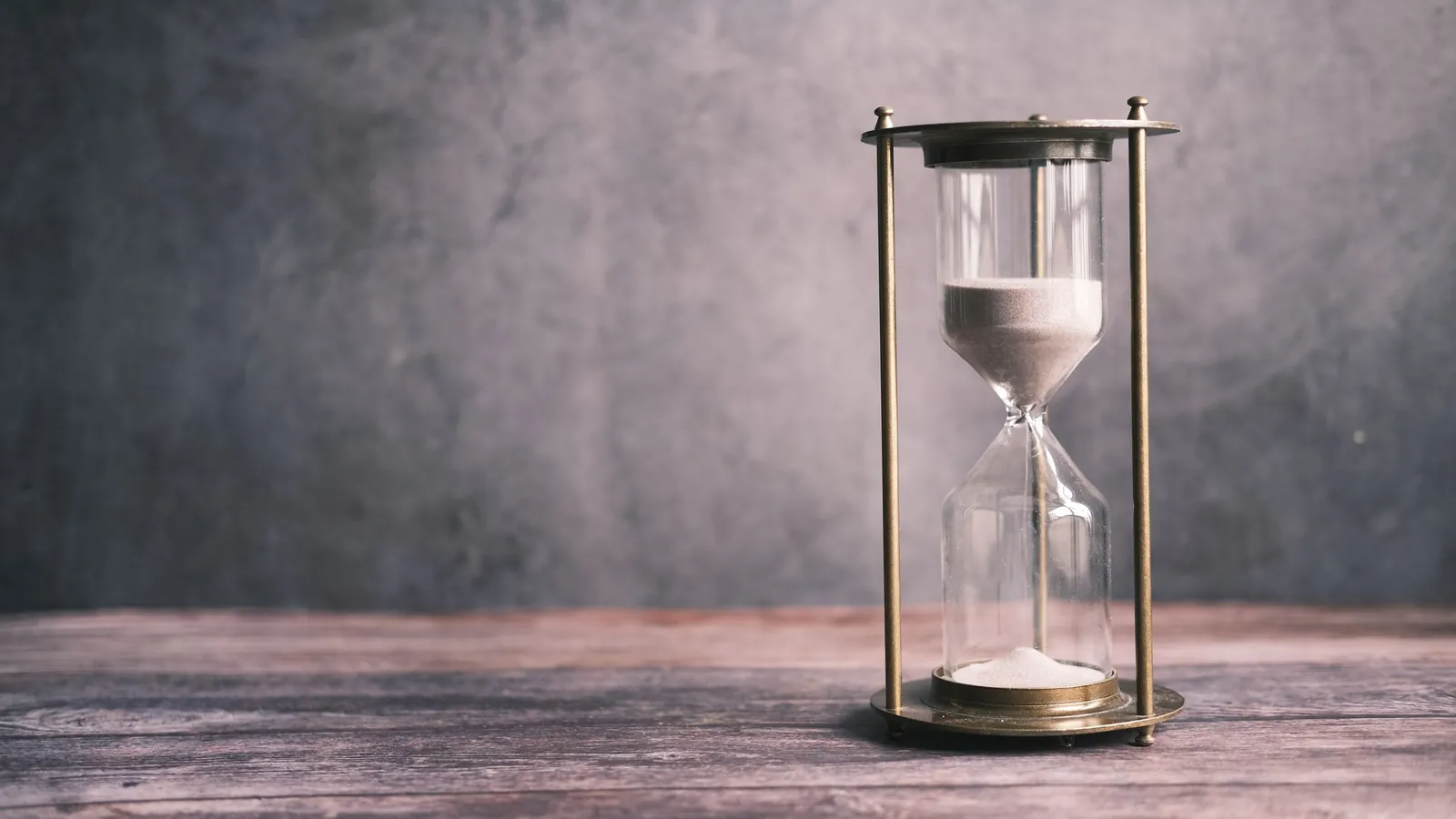 Hourglass with sand running on a wooden table