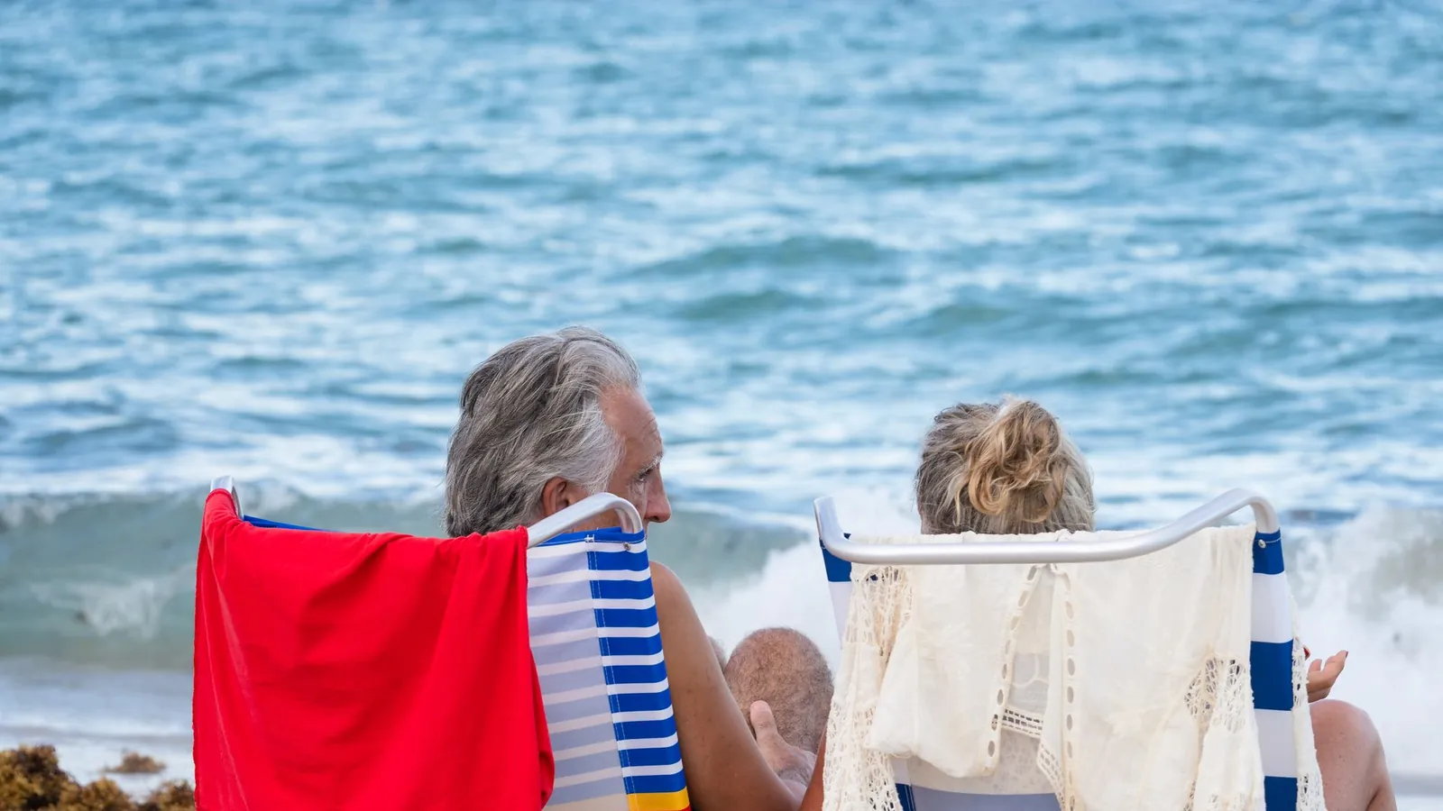 Older couple relaxing in beach chairs facing the waves on Miami Beach, Florida