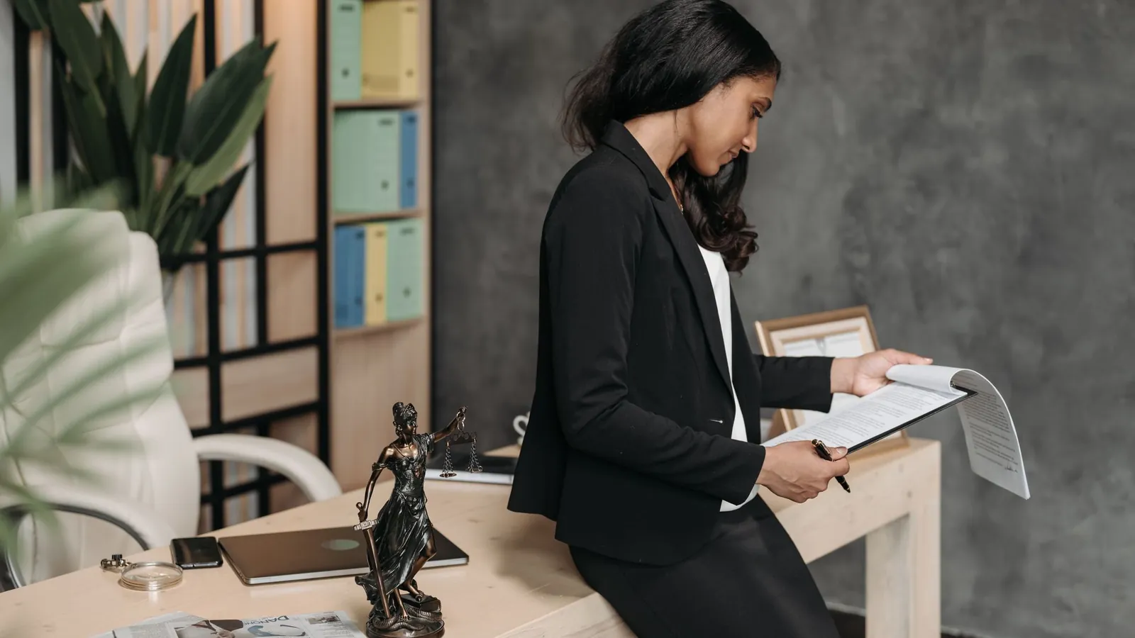 Attorney in a blazer reviewing case documents at her desk