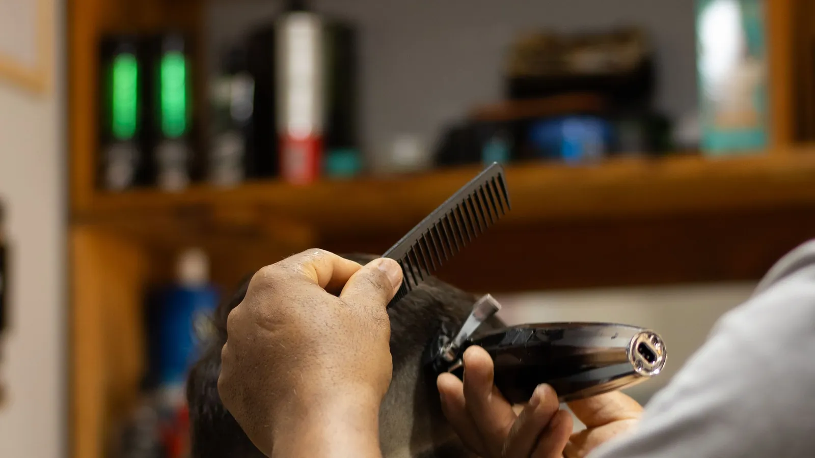 Barber trimming the back of a client's gray hair with clippers