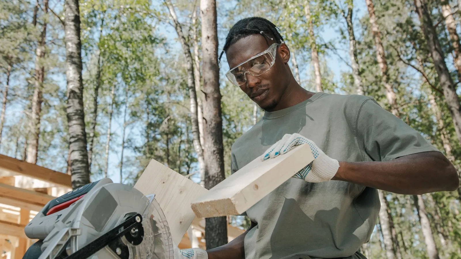 Carpenter cutting a board on a table saw in a wood shop