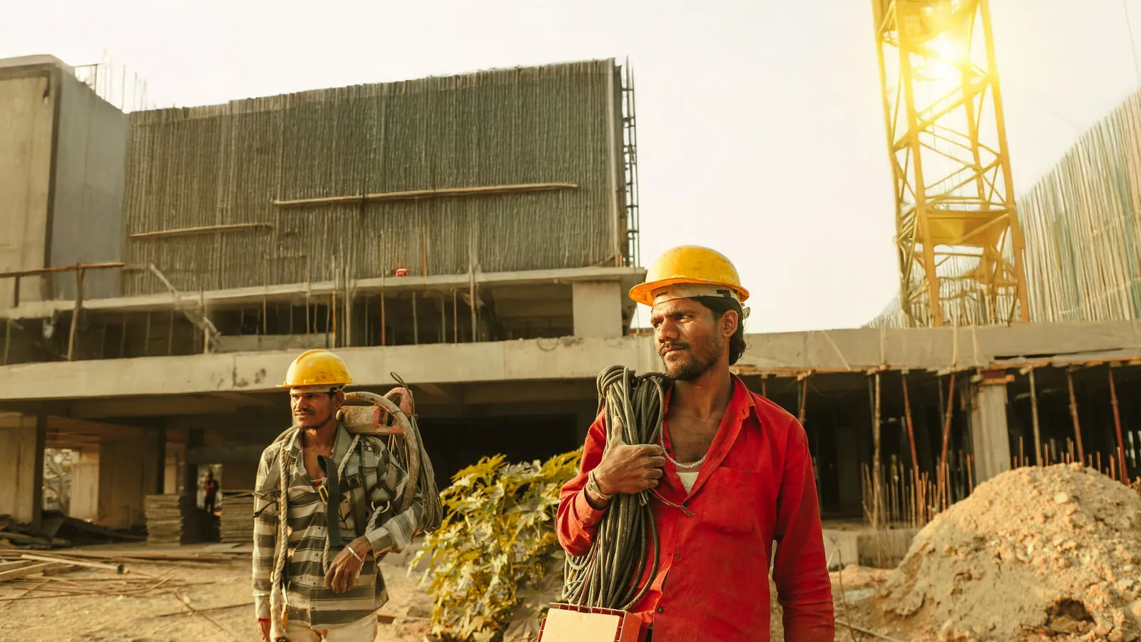 Two construction workers checking a measuring tape at an outdoor job site