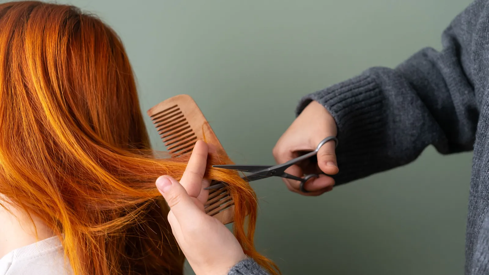 Hair stylist trimming a client's long hair in a bright salon