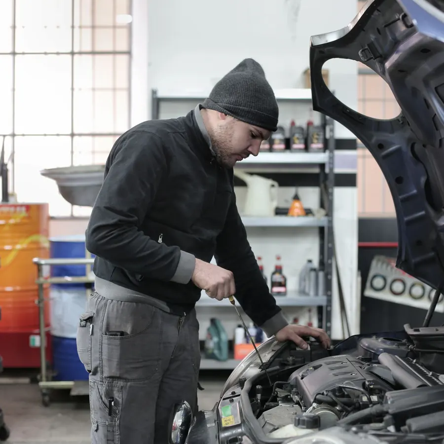 Mechanic looking under the hood of a car in a repair shop
