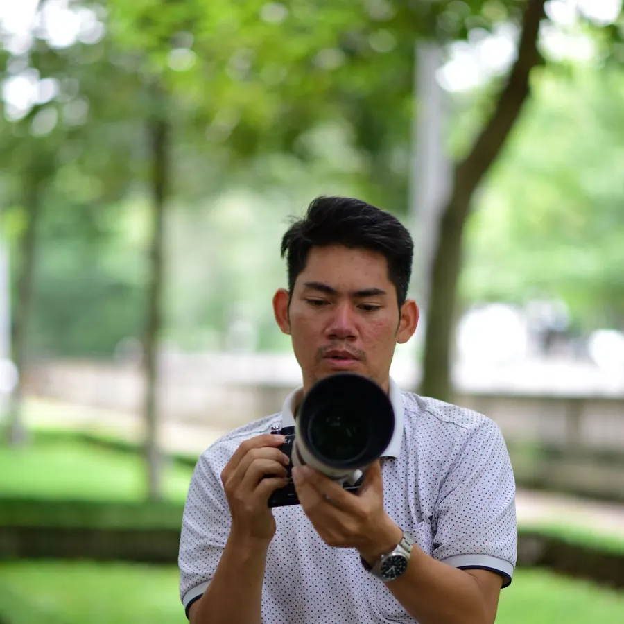 Photographer adjusting a camera with a long lens outdoors