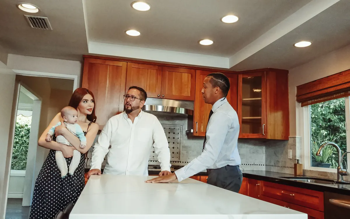 Real estate agent talking with a family holding a baby in a home's kitchen