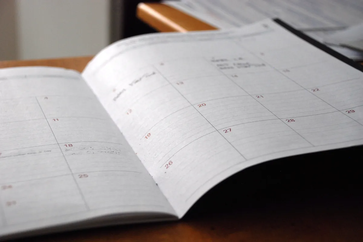 An open monthly paper planner on a wooden desk.