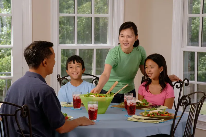 A family of four at a dining table at home, with a salad and drinks.